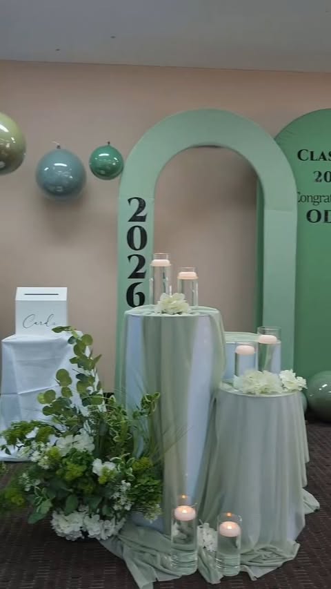 Sage green graduation arch with cocktail tables and candles